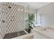 Modern bathroom featuring a frameless glass shower, geometric accent wall, and a standalone soaking tub at 47 Roseclair Se Dr, Atlanta, GA 30317