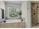 Luxurious bathroom with a soaking tub, tiled shower, and natural light from window at 5925 Water Mark Dr, Cumming, GA 30040