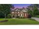 Charming two-story brick home with stone accents, well-manicured lawn, and mature trees during sunset at 5925 Water Mark Dr, Cumming, GA 30040