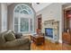 Cozy living room featuring a stone fireplace, built-in shelving, and a large arched window at 5925 Water Mark Dr, Cumming, GA 30040