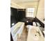 Features a white bathtub, toilet, and sink with dark tile surround and natural light from the window at 1292 Lorenzo Sw Dr, Atlanta, GA 30310
