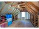 Unfinished attic space featuring wood beams, insulation, and small window for natural light, ideal for future customization at 3335 Ivy Lake Dr, Buford, GA 30519