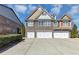 Three-story townhome featuring a brick facade, multi-car garage, neat landscaping, and classic architectural details at 805 Pleasant Hill Nw Rd # 343, Lilburn, GA 30047