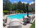 Community pool with lounge chairs, tables, and umbrellas, surrounded by lush landscaping and mature trees on a sunny day at 805 Pleasant Hill Nw Rd # 343, Lilburn, GA 30047