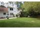 Well-manicured backyard featuring a patio, lush lawn, and mature trees surrounding the two-story white home at , Loganville, GA 30052