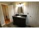 Bathroom vanity with dark cabinets, stone countertop, with a lighted mirror and a wood trimmed door at , Loganville, GA 30052