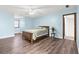 Bedroom with wood-look flooring, blue walls, ceiling fan, and entry to bathroom at 3133 Callie Still Rd, Lawrenceville, GA 30045