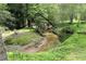 Scenic stream running through lush greenery with a chair placed beside it, creating a serene natural setting at 3133 Callie Still Rd, Lawrenceville, GA 30045