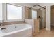 Bathroom featuring a tub and separate glass enclosed shower with tan accent tiles at 3823 Dragon Fly Ln, Loganville, GA 30052