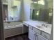 A spacious bathroom featuring a large mirror, white cabinets, a sink, and a soaking tub at 421 Congress Pkwy, Lawrenceville, GA 30044