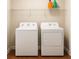 Bright laundry room with white appliances and overhead storage shelf on top of hardwood floors at 421 Congress Pkwy, Lawrenceville, GA 30044