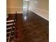 Living room with rich hardwood floors, large bright window, and warm neutral paint, stairs in view at 6399 Boca Grande Blvd, Forest Park, GA 30297