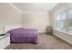 Bedroom with neutral walls, carpet, and a bed with a purple comforter and a window view at 871 Wisteria View Ct, Dacula, GA 30019