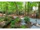 Secluded backyard retreat featuring a serene stream, lush greenery, and a charming seating area at 1560 Bubbling Creek Ne Rd, Atlanta, GA 30319