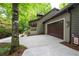 Side exterior view showcasing the attached garage, front porch, and wooded surroundings of the home at 1560 Bubbling Creek Ne Rd, Atlanta, GA 30319