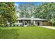 Charming brick home with a well-manicured lawn and covered carport, complemented by mature trees and landscaping at 233 Dorris Sw Dr, Marietta, GA 30060