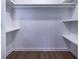 Bright walk-in closet with wood-look flooring and shelving on the sides and in the back at 550 Oglesby Bridge Se Rd, Conyers, GA 30094