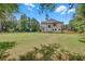 Large backyard view of a two-story home surrounded by mature trees and a fenced perimeter at 1461 Leach Dr, Lawrenceville, GA 30045