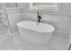 Contemporary bathroom with a sleek standalone tub, black hardware, marble wall and floor tile, and bright window at 1461 Leach Dr, Lawrenceville, GA 30045