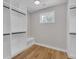 Walk-in closet with wood floors, custom shelves and hanging racks, with bench and a window providing natural light at 1461 Leach Dr, Lawrenceville, GA 30045