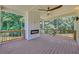 Covered deck with fireplace, ceiling fan, wood floors, black railings, and outdoor seating area overlooking green trees at 1461 Leach Dr, Lawrenceville, GA 30045