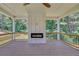 Wide view of the home's covered outdoor deck with a gas fireplace and ceiling fan with a view of the surrounding trees at 1461 Leach Dr, Lawrenceville, GA 30045