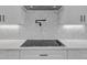 Modern kitchen features a black cooktop, white cabinets, backsplash tiling, and pot filler at 1461 Leach Dr, Lawrenceville, GA 30045