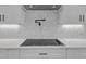 Modern cooktop, white countertops, gray backsplash, and stainless steel vent hood at 1461 Leach Dr, Lawrenceville, GA 30045