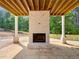 Outdoor fireplace on a covered patio with exposed wood beams and a view of the wooded backyard at 1461 Leach Dr, Lawrenceville, GA 30045