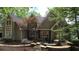 Stunning exterior of home with stone accents, a well-manicured lawn, and lush greenery, showcasing elegance at 3800 Schooner Rdg, Alpharetta, GA 30005