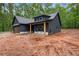 Contemporary home featuring dark gray siding, natural wood columns, and an attached garage, surrounded by nature at 1687 Harmony Rd, Temple, GA 30179