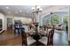 Open-concept dining area with a glass-top table, wooden chairs, hardwood floors, and adjacent living spaces at 10830 Carrara Cv, Alpharetta, GA 30022