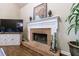 Living room featuring a brick fireplace, a flat-screen TV, and a decorative mantel with hardwood floors at 10830 Carrara Cv, Alpharetta, GA 30022