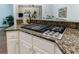 Close-up of the kitchen island with granite countertop and a modern gas cooktop with stainless steel knobs at 10830 Carrara Cv, Alpharetta, GA 30022