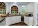 Bright kitchen with white cabinetry, granite countertops, and a wine cooler, all illuminated by arched windows at 10830 Carrara Cv, Alpharetta, GA 30022