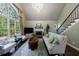 Elegant living room with large windows, a fireplace, hardwood floors, comfortable seating, and a staircase at 10830 Carrara Cv, Alpharetta, GA 30022