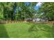 A large backyard with green grass, surrounded by a wooden fence and lush trees at 3275 Dodson Dr, East Point, GA 30344