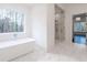 Bright bathroom featuring a free-standing tub and a glass-enclosed shower with marble tile surround at 5211 Powers Ferry Rd, Sandy Springs, GA 30327