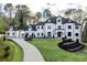 Elegant home exterior with a manicured lawn, circular driveway, and classic architectural details at 5211 Powers Ferry Rd, Sandy Springs, GA 30327