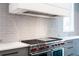 Gourmet kitchen featuring a stainless steel range, custom hood, and glossy backsplash at 5211 Powers Ferry Rd, Sandy Springs, GA 30327
