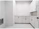 Bright laundry room featuring white cabinets, stone countertop, and tile floors at 5211 Powers Ferry Rd, Sandy Springs, GA 30327
