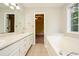 This bathroom features a soaking tub, white cabinets and tile flooring at 85 Chestnut Dr, Covington, GA 30016