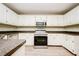 Bright kitchen with white cabinetry, stainless steel appliances, and dark countertops, creating a functional cooking space at 85 Chestnut Dr, Covington, GA 30016