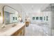 Bright, elegant bathroom with marble floors, glass shower, soaking tub, and dual vanities with gold accents at 3379 Rennes Ne Dr, Brookhaven, GA 30319