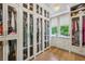 Walk-in closet featuring glass-front cabinets, hardwood floors, and a window with backyard views at 3379 Rennes Ne Dr, Brookhaven, GA 30319