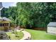 An inviting backyard patio featuring outdoor seating, grill, storage building, and a lush lawn at 452 Emerald Trce, Jonesboro, GA 30236