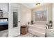 Bright bathroom featuring a soaking tub, wood floors, and a door with a mirrored panel at 4150 E Chapel Hill Rd, Douglasville, GA 30135