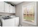 Bright laundry room with storage cabinets and a large window with backyard views at 4150 E Chapel Hill Rd, Douglasville, GA 30135