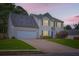 Charming home at twilight featuring stone accents, manicured lawn, and an attached two-car garage at 1070 Evergreen Oak Way, Dacula, GA 30019