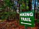 A hiking trail surrounded by lush trees, marked by a clear green sign at 8088 Lakeview Pkwy, Villa Rica, GA 30180